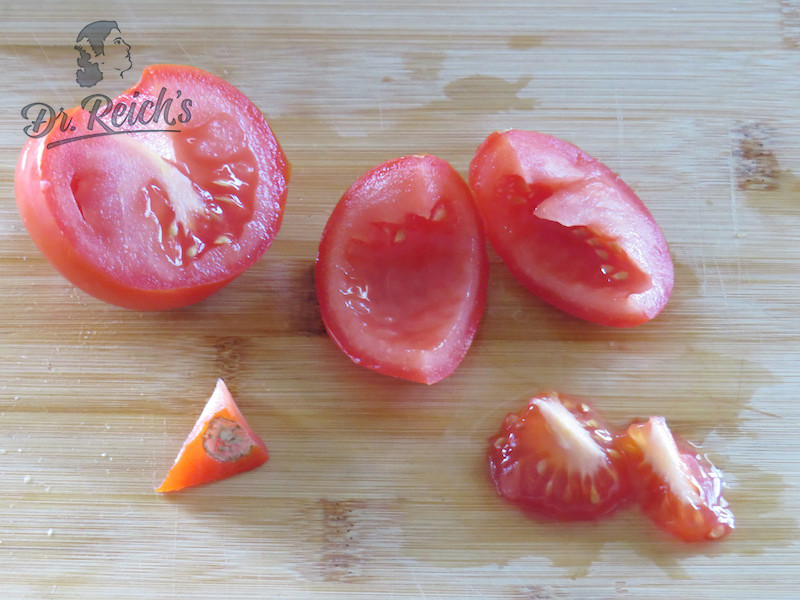 Tomate halbieren, entstielen, entkernen und schneiden